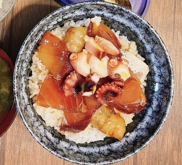bowl of rice topped with slices of seafood